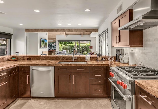 kitchen with wall chimney range hood, sink, appliances with stainless steel finishes, tasteful backsplash, and beam ceiling