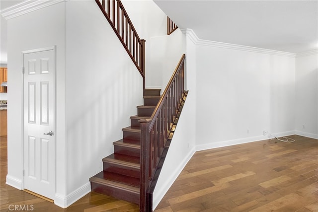 staircase with ornamental molding and hardwood / wood-style floors