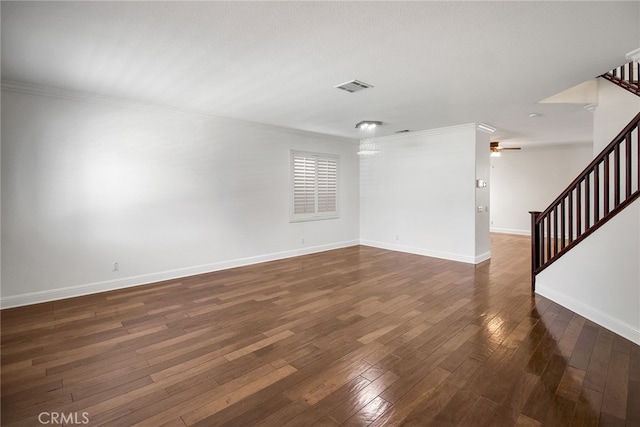 empty room featuring crown molding, an inviting chandelier, and dark wood-type flooring