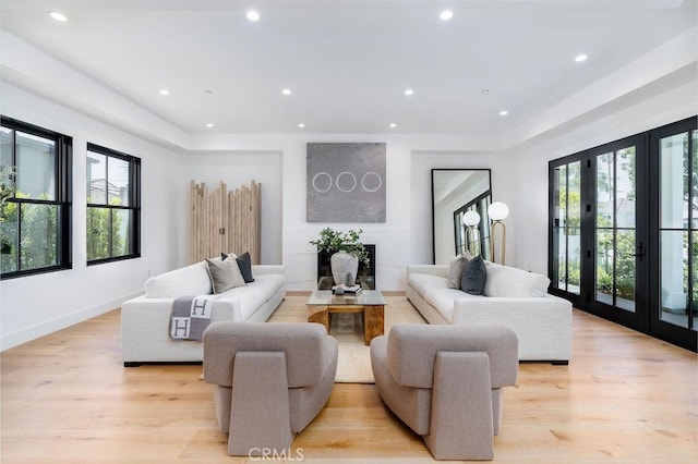 living room featuring a healthy amount of sunlight, french doors, and light hardwood / wood-style flooring