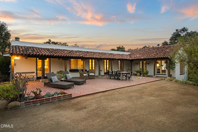 back house at dusk with a patio area