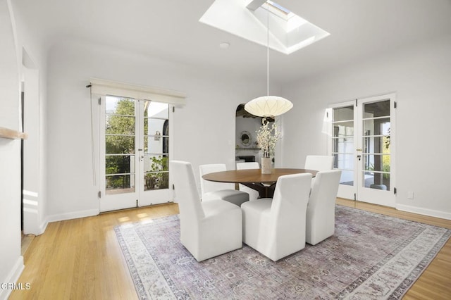 dining area with a skylight, wood finished floors, and baseboards