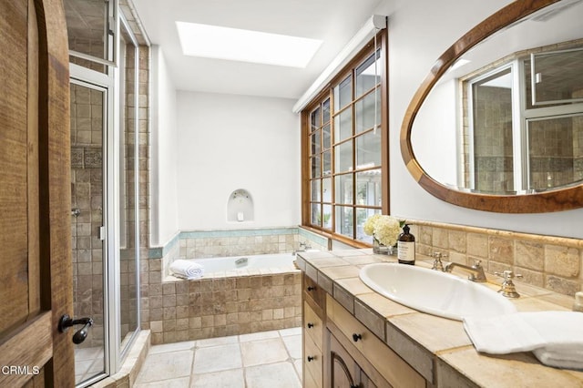 full bathroom featuring vanity, a skylight, tile patterned flooring, a shower stall, and a garden tub