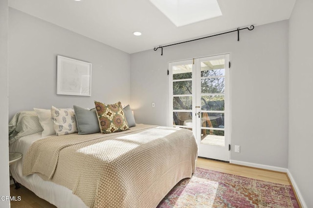 bedroom with wood finished floors, recessed lighting, french doors, a skylight, and baseboards