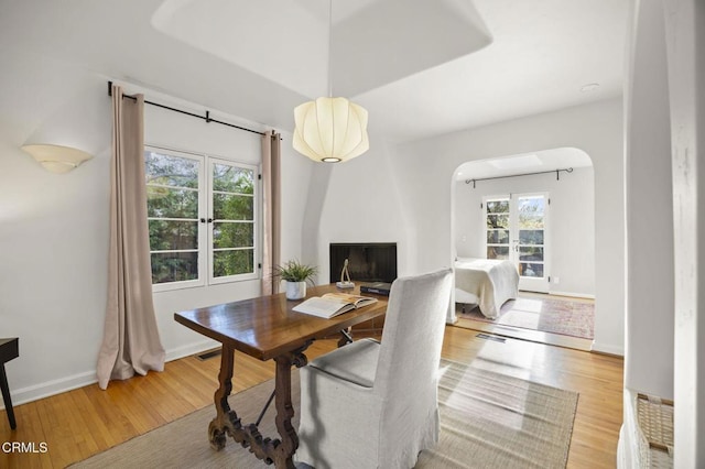 office space featuring baseboards, arched walkways, visible vents, and wood finished floors