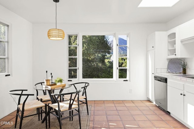 kitchen with hanging light fixtures, white cabinets, glass insert cabinets, and stainless steel dishwasher