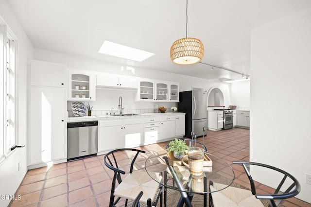 kitchen with a sink, white cabinetry, appliances with stainless steel finishes, a skylight, and light countertops