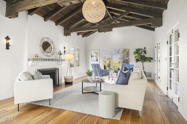 living area with beam ceiling, a fireplace with flush hearth, high vaulted ceiling, hardwood / wood-style flooring, and wood ceiling