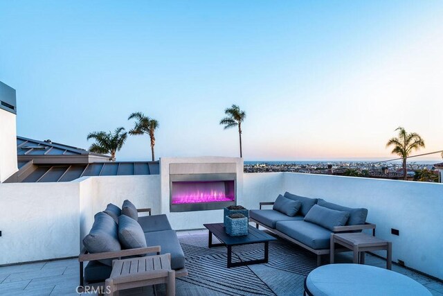 patio terrace at dusk with an outdoor living space with a fireplace