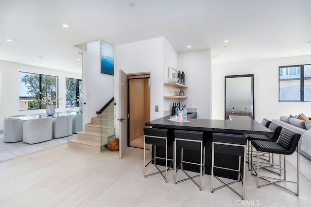 kitchen featuring a breakfast bar, kitchen peninsula, and light tile patterned floors