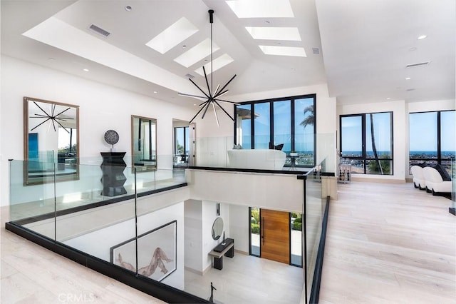 kitchen featuring a skylight, high vaulted ceiling, and light hardwood / wood-style floors