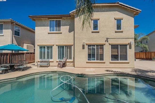 rear view of house with a fenced in pool and a patio area