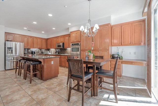 kitchen with appliances with stainless steel finishes, pendant lighting, tasteful backsplash, an island with sink, and a breakfast bar area