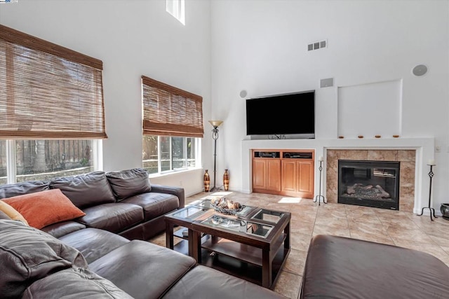 living room featuring light tile patterned floors, a towering ceiling, and a tile fireplace