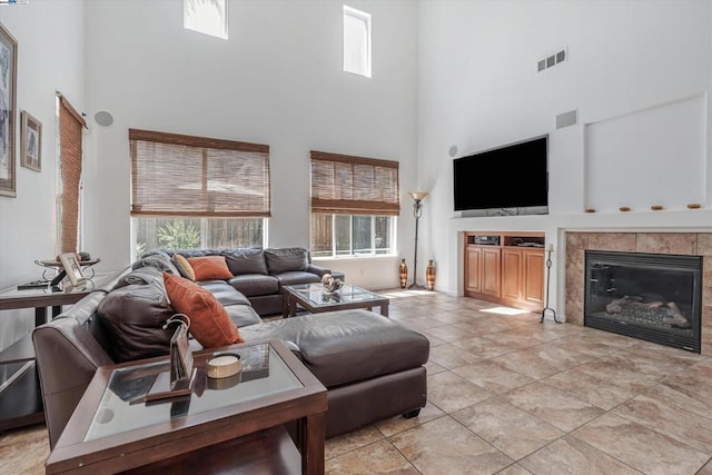 tiled living room with a towering ceiling and a fireplace