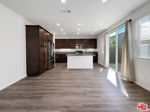 kitchen featuring a kitchen island with sink, sink, stainless steel appliances, and light hardwood / wood-style floors