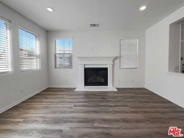 unfurnished living room featuring plenty of natural light and dark wood-type flooring