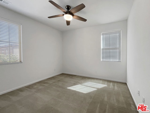 carpeted spare room featuring ceiling fan