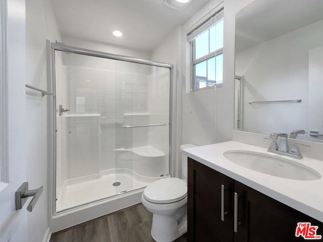 bathroom with toilet, hardwood / wood-style floors, vanity, and walk in shower