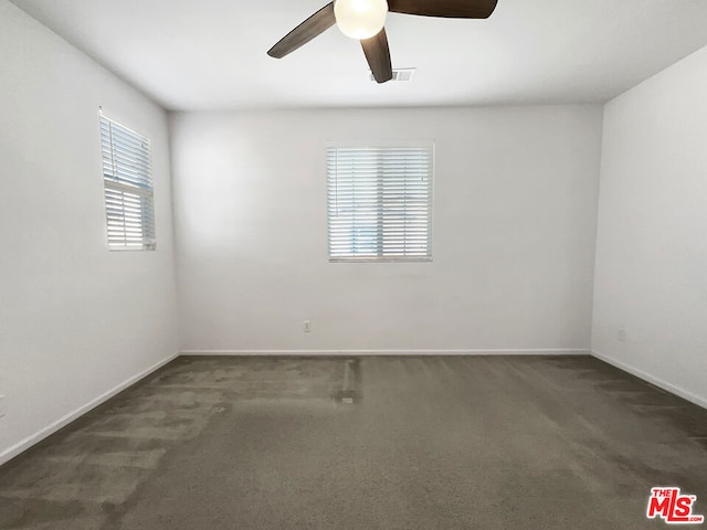 spare room featuring ceiling fan and dark carpet