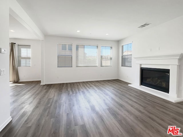 unfurnished living room featuring dark hardwood / wood-style flooring and plenty of natural light