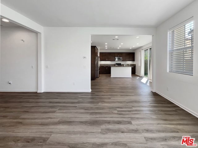 unfurnished living room featuring a wealth of natural light and dark wood-type flooring