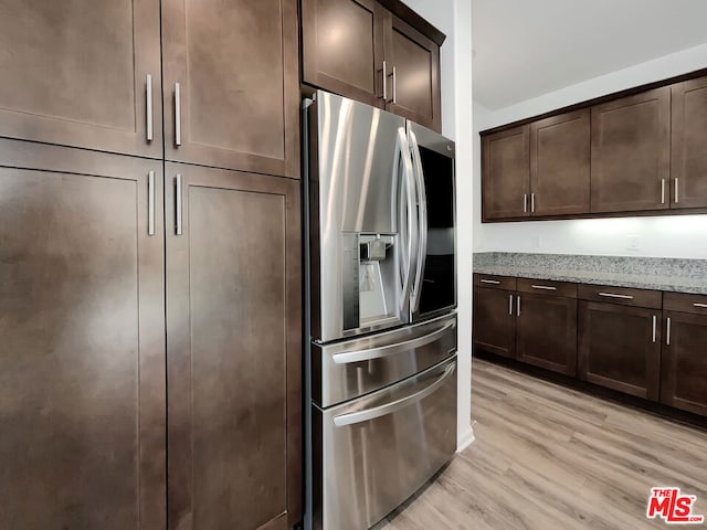 kitchen with stainless steel fridge with ice dispenser, light hardwood / wood-style flooring, dark brown cabinets, and light stone counters