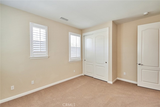 unfurnished bedroom with light carpet and a closet