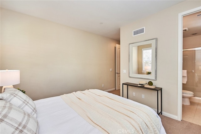 bedroom with ensuite bathroom and light tile patterned flooring