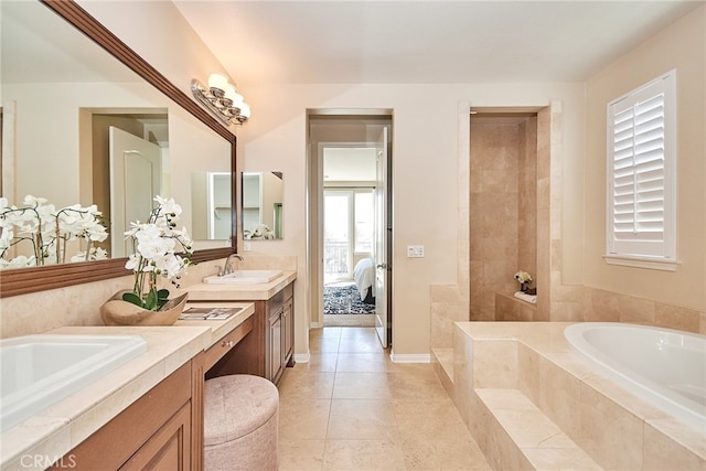 bathroom with tile patterned floors, tiled tub, and vanity