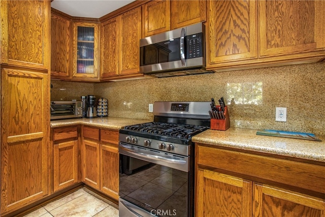 kitchen featuring backsplash, appliances with stainless steel finishes, and light tile patterned floors