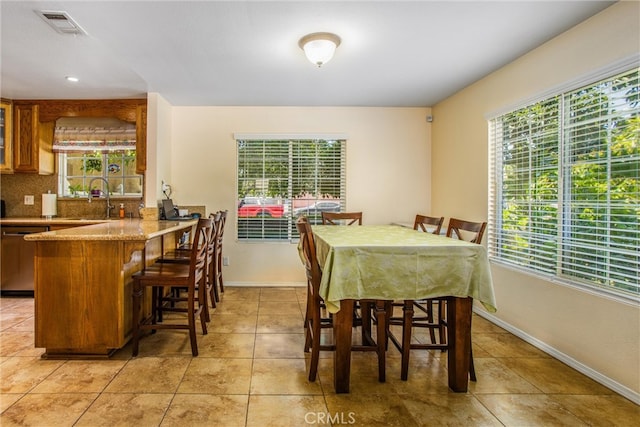 dining area featuring a wealth of natural light, wet bar, and light tile patterned floors