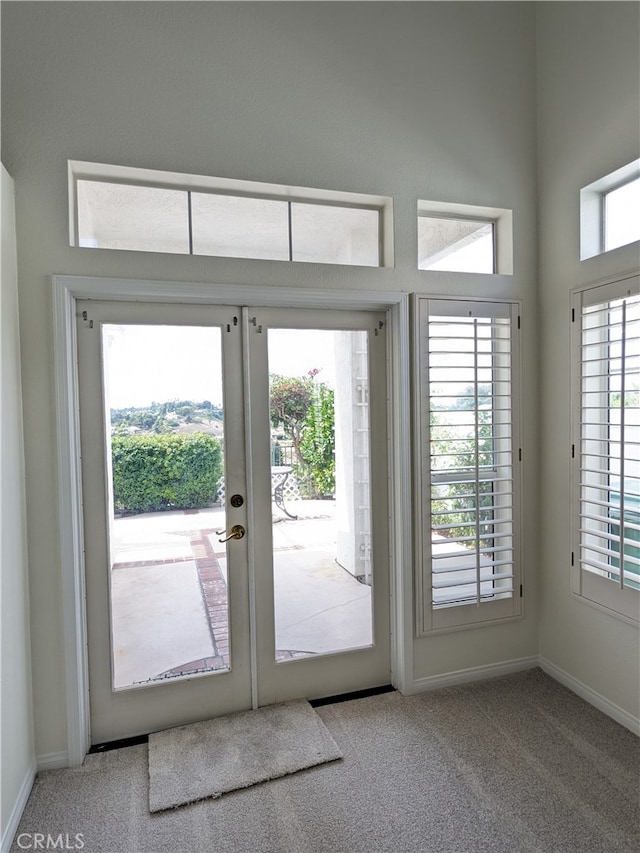 doorway to outside with light carpet, a wealth of natural light, and french doors