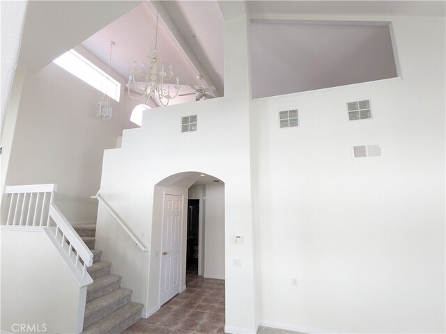 stairway featuring a towering ceiling and a chandelier