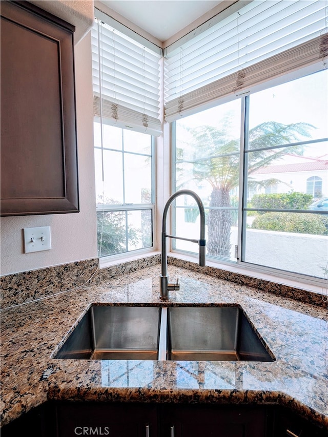 interior details featuring dark brown cabinets, sink, and light stone counters