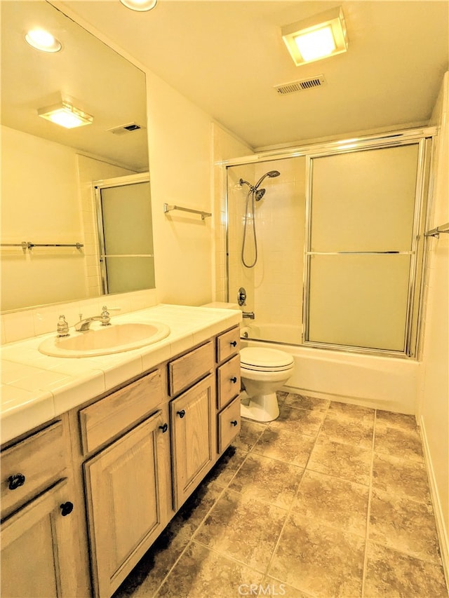 full bathroom featuring bath / shower combo with glass door, vanity, and toilet