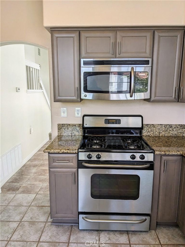 3310 Tripoli Way, Oceanside, CA 92056 - kitchen featuring stainless steel appliances, arched walkways, gray cabinetry, and stone counters