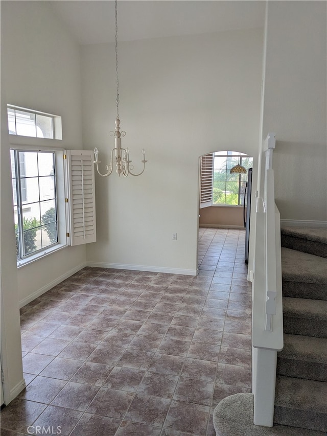 unfurnished dining area featuring high vaulted ceiling, tile patterned flooring, an inviting chandelier, and a healthy amount of sunlight