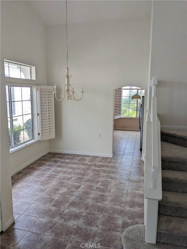 3310 Tripoli Way, Oceanside, CA 92056 - unfurnished dining area featuring a towering ceiling, a chandelier, stairway, and baseboards
