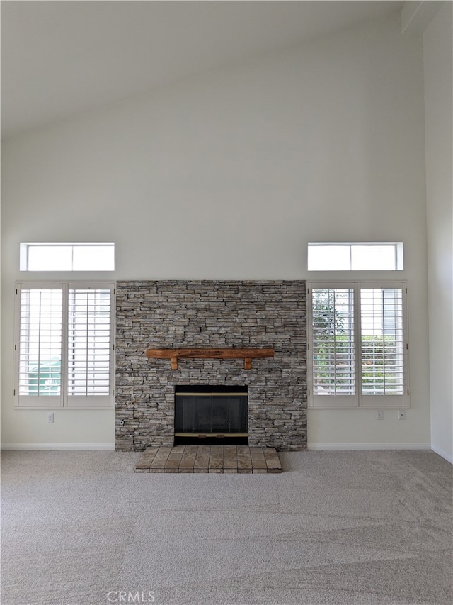 unfurnished living room featuring high vaulted ceiling, carpet floors, and a stone fireplace