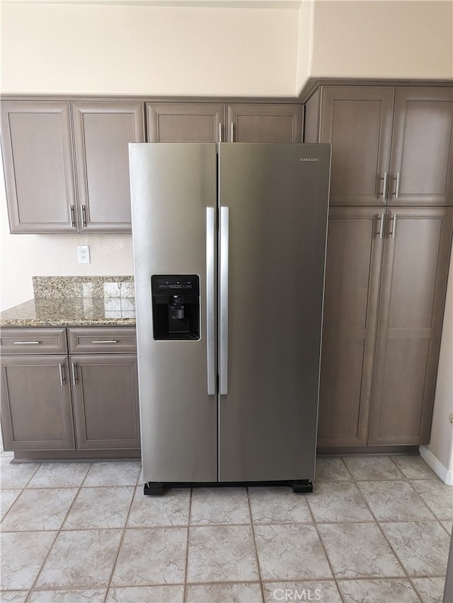 kitchen with light stone countertops and stainless steel fridge with ice dispenser