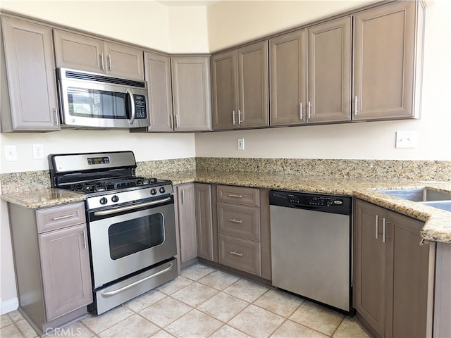 kitchen featuring light stone countertops, appliances with stainless steel finishes, and light tile patterned floors