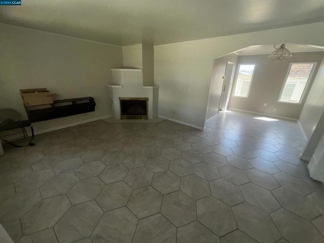 unfurnished living room with a fireplace and a chandelier