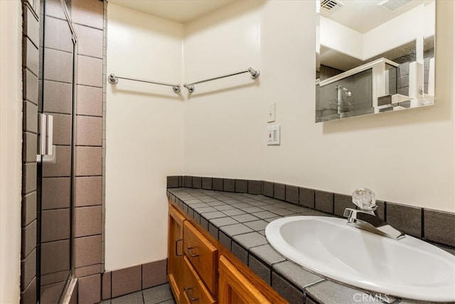 bathroom with walk in shower, vanity, and tile patterned floors