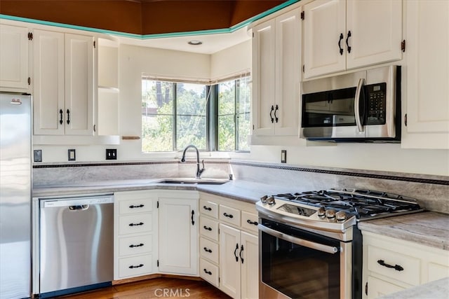 kitchen with white cabinets, wood-type flooring, appliances with stainless steel finishes, and sink