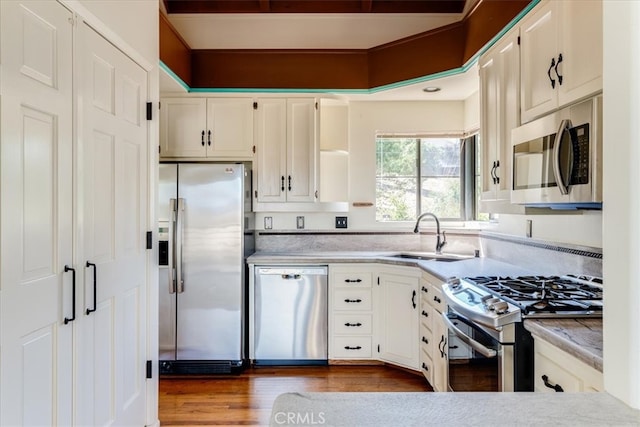 kitchen featuring white cabinets, sink, stainless steel appliances, and hardwood / wood-style flooring