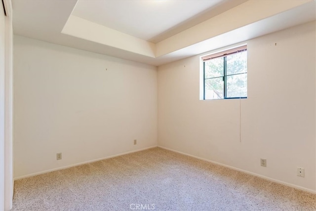 carpeted empty room featuring a raised ceiling