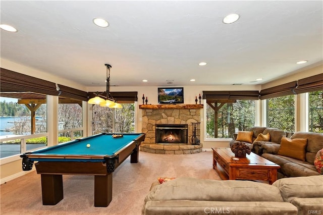 rec room featuring a water view, light colored carpet, a fireplace, and a healthy amount of sunlight