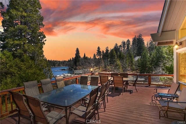 deck at dusk featuring a water view