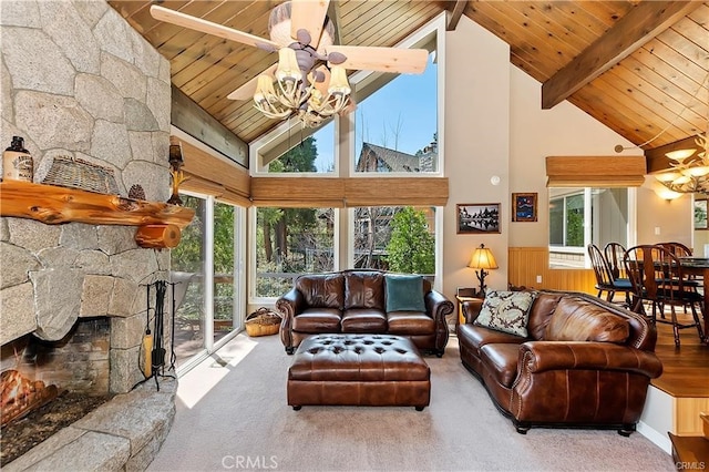 carpeted living room featuring ceiling fan, beamed ceiling, a stone fireplace, wooden walls, and high vaulted ceiling